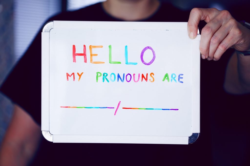 Person holding up sign with the text 'Hello my pronouns are....'