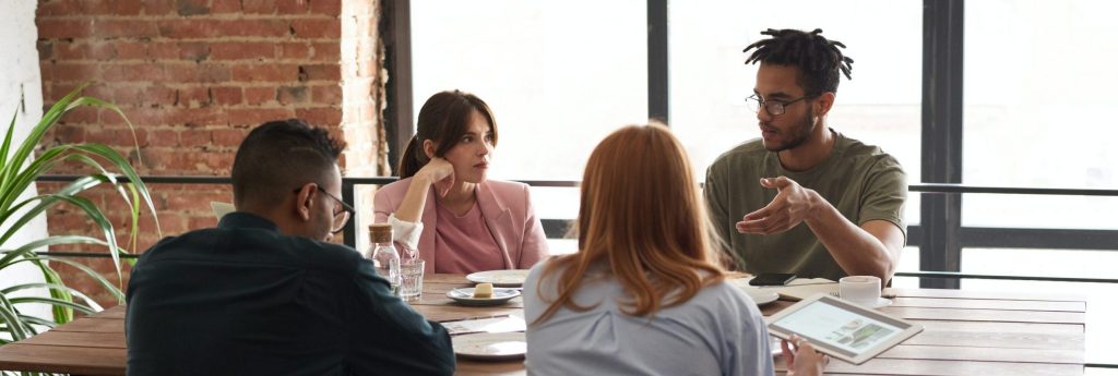 A photo of four team members having a discussion during a meeting.